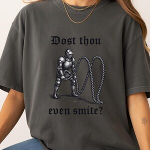 Puede incluir: Camiseta gris oscuro con el texto "Dost thou even smite?" encima y debajo de una ilustraci&oacute;n en blanco y negro de un caballero con armadura sosteniendo una cuerda.