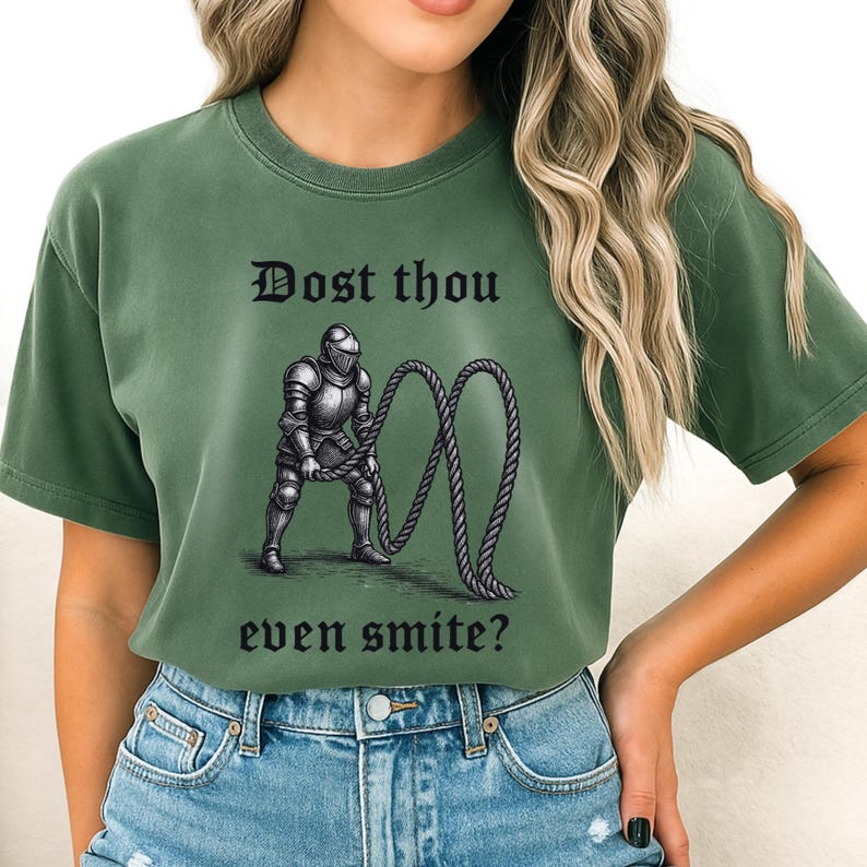 Puede incluir: Camiseta verde con el texto "Dost thou even smite?" sobre una ilustraci&oacute;n de un caballero con armadura sosteniendo una cuerda. La camiseta es de color liso y tiene cuello redondo.