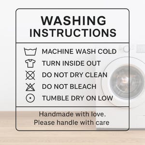 May include: A white sign with black text that reads "WASHING INSTRUCTIONS." The sign includes symbols and instructions: machine wash cold, turn inside out, do not dry clean, do not bleach, and tumble dry on low. The sign also says "Handmade with love. Please handle with care."