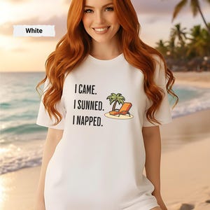 Puede incluir: Camiseta blanca con el texto "I CAME. I SUNNED. I NAPPED." y un gráfico de una palmera y una tumbona. La camiseta es de cuello redondo.