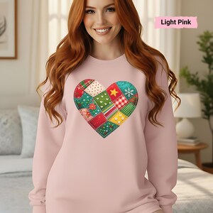 May include: Light pink sweatshirt featuring a patchwork heart design. The heart is composed of various fabric patterns, including floral, polka dot, and plaid, with a star and snowflake. The text "Light Pink" is displayed in a pink rectangle.