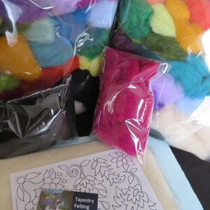 May include: A needle felting kit with a variety of colored wool fibers in plastic bags, a black felting mat, and a set of felting needles. The kit also includes a pattern for a floral design. "Tapestry Felting Needles" is printed on the needle packaging.