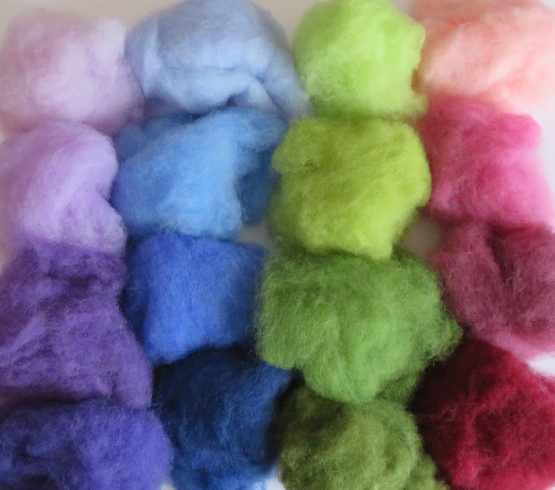 May include: A collection of colorful wool roving in various shades of purple, blue, green, pink, and red. The wool is arranged in rows, with each row featuring a different color.