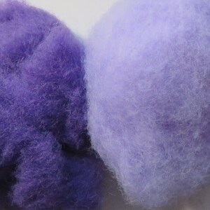 May include: Four balls of wool yarn in shades of purple, blue, and lavender. The yarn is soft and fluffy, and it would be perfect for knitting or crocheting.