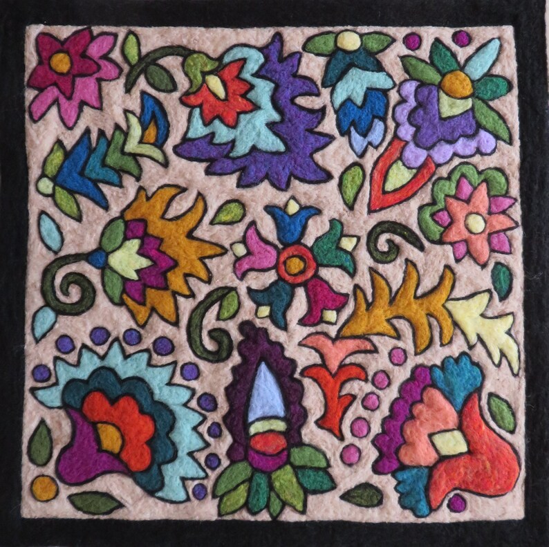 May include: A beige fabric square with a black border, featuring a colorful embroidered design of various flowers and leaves. The design includes shades of pink, purple, blue, green, yellow, and orange.