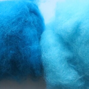 May include: Four balls of wool yarn in shades of blue and green. The yarn is soft and fluffy, and it would be perfect for knitting or crocheting.