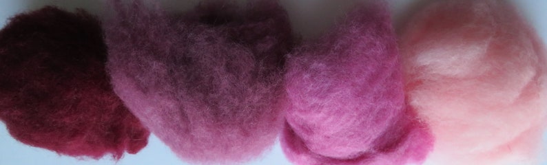 May include: Four samples of wool roving in different shades of pink, from dark burgundy to light pink.
