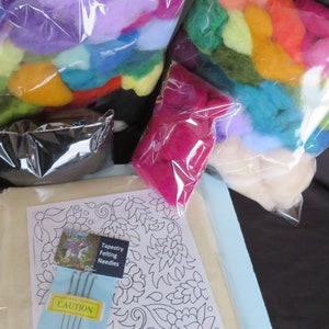May include: A needle felting kit with a white fabric base, a floral design printed on it, and a bag of colorful wool fibers. The kit also includes a package of felting needles and a caution label.