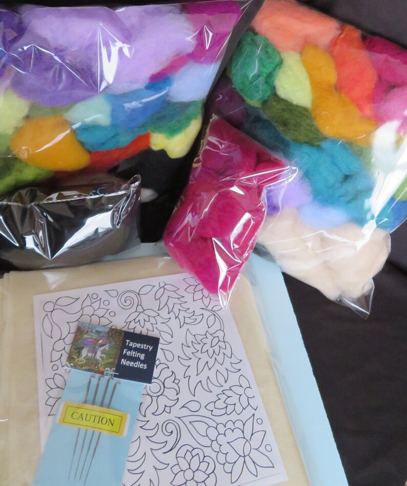 May include: A needle felting kit with a white fabric base, a floral design printed on it, and a bag of colorful wool fibers. The kit also includes a package of felting needles and a caution label.