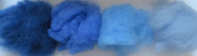May include: Four samples of blue wool fiber, ranging in shade from dark blue to light blue.