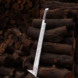 Puede incluir: Una espada grande, de color plateado, con una hoja texturizada y un mango envuelto. La espada tiene un diseño angular único en la punta. El texto "ArmadaCraft" es visible en la hoja. La espada se muestra contra un fondo de troncos apilados.