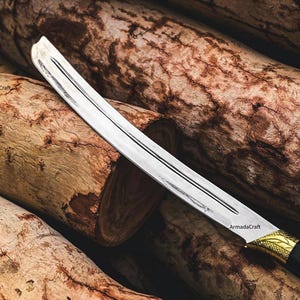 May include: A curved, silver blade sword with a black and gold handle. The blade has a central groove and is set against a backdrop of textured, brown wooden logs. The sword's handle features intricate gold detailing.