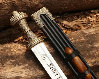 May include: A detailed image of a decorative sword with a silver blade and ornate gold-colored handle. The blade has the text "Fetter L" and a symbol. The sword is next to a black sheath with a wooden handle.