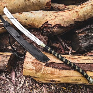 May include: A silver and gold sword with a black handle and sheath rests on a pile of logs. The sword has a curved blade and a decorative handle wrapped in black leather with gold accents. The sheath is black leather.