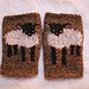 May include: A pair of brown knitted wrist warmers with a white sheep and black face design.