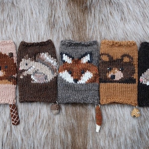 May include: Five knitted fingerless gloves with animal faces. The gloves are brown, gray, beige, black, and orange. Each glove has a small knitted tail attached.