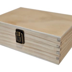 May include: A rectangular wooden box with a light brown finish. The box has a hinged lid and a metal clasp closure. The wood grain is visible, and the box appears to be new.