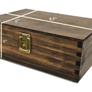 May include: A rectangular wooden box with a dark brown finish. The box is 8.5 inches long, 6 inches wide, and 3 inches high. It features a brass-colored latch and hinges. The box is constructed with dovetail joints.