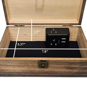 May include: Open wooden box with a black interior and a black power adapter. The box is 7.8 inches wide, 5.37 inches deep, and 2.5 inches high. The box has a metal clasp.