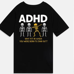 Könnte beinhalten: Schwarzes T-Shirt mit dem Wort "ADHS" in Weiß über einer Grafik von Skeletten. Ein Skelett ist gelb und macht einen Dab. Der Text "WHY FIT IN WHEN YOU WERE BORN TO STAND OUT?" steht unter den Skeletten.