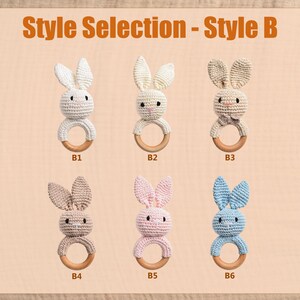 May include: A selection of six crochet bunny teethers in various colors, including white, cream, tan, pink, and blue. Each bunny has a wooden ring and is labeled with a style number. The text "Style Selection - Style B" is at the top.