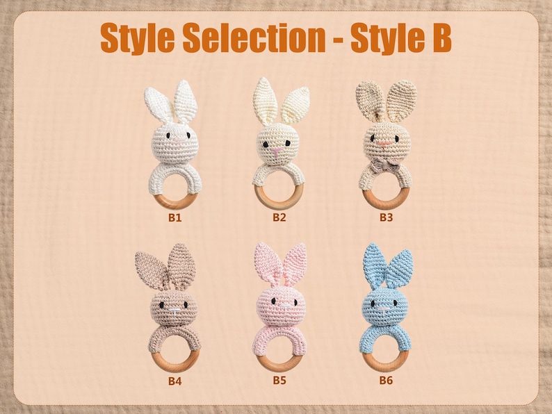 May include: A selection of six crochet bunny teethers in various colors, including white, cream, tan, pink, and blue. Each bunny has a wooden ring and is labeled with a style number. The text "Style Selection - Style B" is at the top.