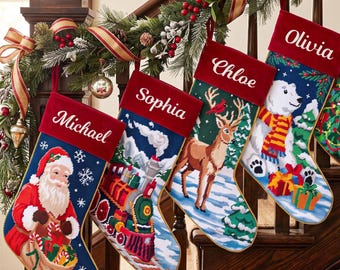 May include: Four personalized Christmas stockings with red velvet cuffs featuring the names Michael, Sophia, Chloe, and Olivia. The stockings display needlepoint designs of Santa Claus, a steam train, a deer, and a polar bear with gifts.