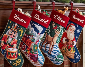 May include: Four personalized Christmas stockings with red velvet cuffs featuring the names Emma, Daniel, Chloe, and Samuel. The stockings display needlepoint designs of a nutcracker, a steam train, a reindeer, and Santa Claus.