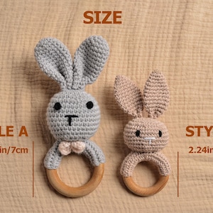 May include: Two crochet bunny rattles, Style A in gray with a pink bow tie, and Style B in tan. Each bunny has a wooden ring base. Style A measures 2.75 inches (7cm) and Style B measures 2.24 inches (5.7cm).