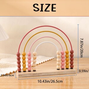 May include: A wooden rainbow abacus toy with colorful beads and arched wires. The abacus is 10.43 inches long, 7.87 inches high, and 0.59 inches thick. The word "SIZE" is printed at the top of the image.