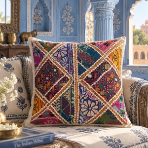 May include: A square throw pillow featuring a vibrant patchwork design of diamond-shaped fabric panels. The panels display various colors including red, blue, yellow, and green, accented with intricate embroidery, floral patterns, and small reflective mirrors.