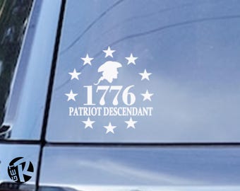 Op de afbeelding: Witte vinyl sticker met de tekst "1776 PATRIOT DESCENDANT", een silhouet van een persoon met een steek en sterren. De sticker is ontworpen om op een autoruit of een vergelijkbaar oppervlak te worden aangebracht.