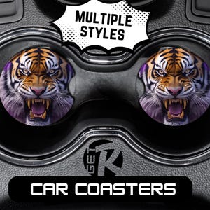 May include: Two car coasters featuring a snarling tiger face with orange, black, and white fur, and purple accents. The coasters are round and fit into a car's cup holders. The text "MULTIPLE STYLES" and "CAR COASTERS" are also visible.