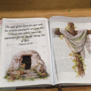 May include: An open book featuring a translucent overlay with the text 'The eyes of the Lord are upon even the weakest worshipers who love him – those who wait in hope and expectation for the strong, steady love of God. Psalms 33:18' and a stone tomb illustration, plus a cross draped in fabric.