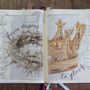 Peut inclure: Livre ouvert avec des illustrations artistiques. Une page présente une couronne d'épines avec les mots "from thorns". La page opposée affiche une couronne dorée avec les mots "La glory".