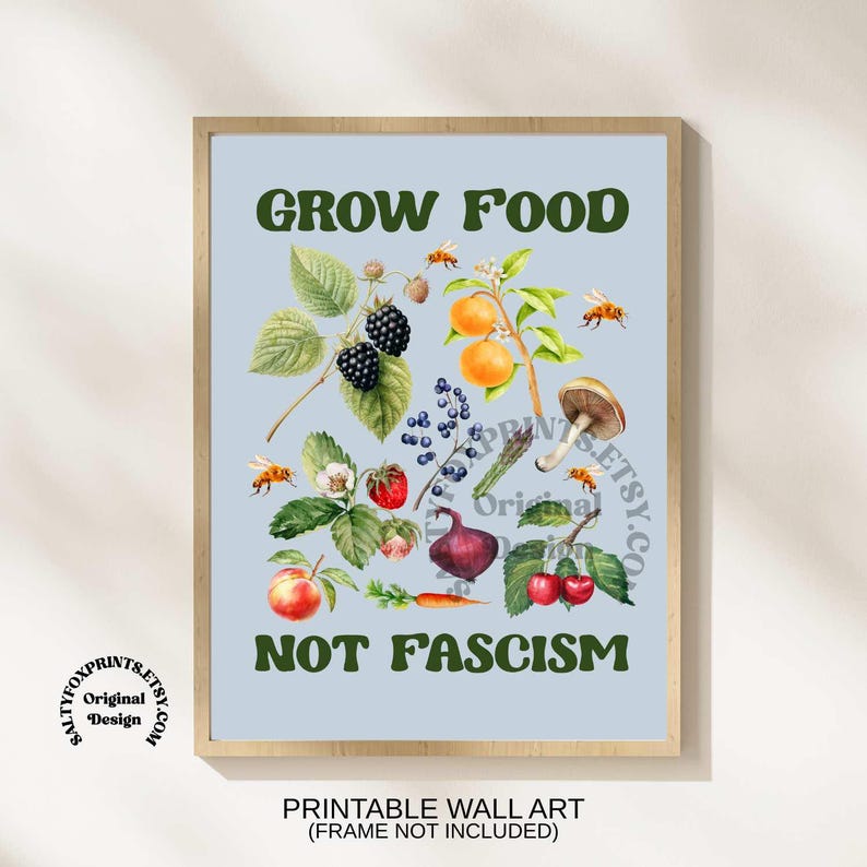 Peut inclure: Impression d'art encadr&eacute;e avec un fond bleu clair. L'illustration pr&eacute;sente des aquarelles de fruits, l&eacute;gumes et abeilles, avec le texte "GROW FOOD NOT FASCISM". Le cadre est en bois.