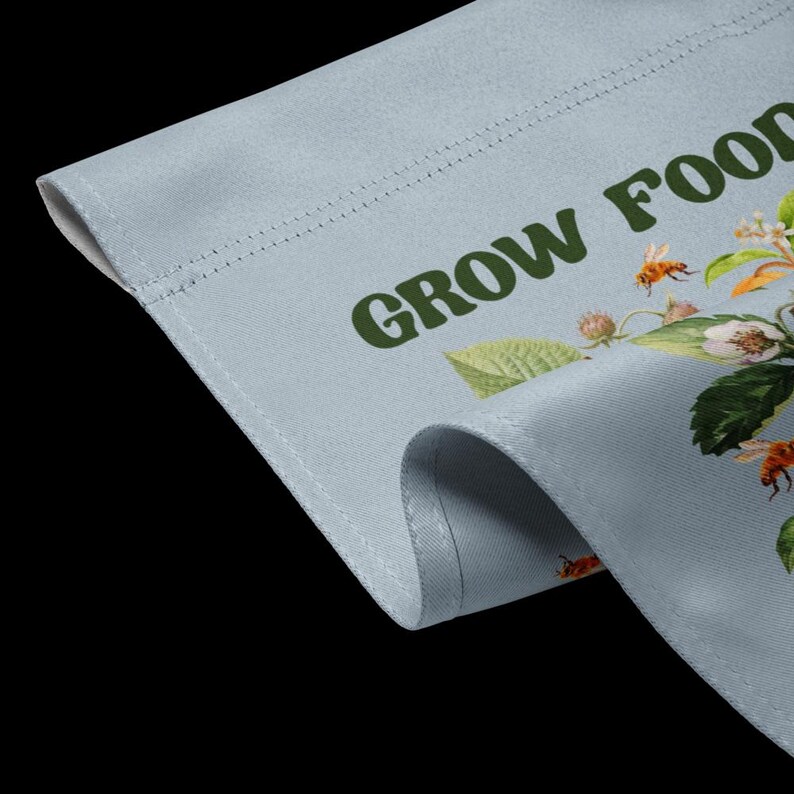 May include: A light blue canvas garden flag with the text "GROW FOOD" in green letters. The flag is decorated with a floral design featuring bees, leaves, and flowers.