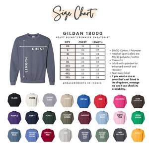 K&ouml;nnte beinhalten: Gr&ouml;&szlig;entabelle f&uuml;r Gildan 18000 Heavy Blend Crewneck Sweatshirts. Die Tabelle zeigt Brust- und L&auml;ngenma&szlig;e in Zoll f&uuml;r die Gr&ouml;&szlig;en XS bis 5XL. Die Tabelle listet auch die Stoffzusammensetzung und Passformdetails auf. Ein Farbmuster-Diagramm zeigt 18 verschiedene Farben.