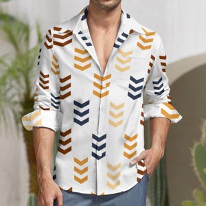 May include: White button-down shirt with a repeating chevron pattern in shades of brown, navy, and yellow. The shirt has long sleeves, a chest pocket, and a classic collar. The cuffs and collar have a contrasting trim.