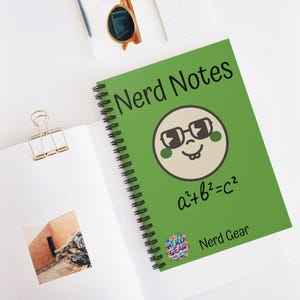 May include: A spiral-bound notebook with a green cover featuring the text "Nerd Notes" and a cartoon face wearing glasses. Below the face is the equation a²+b²=c². The notebook also has the text "Nerd Gear" at the bottom.