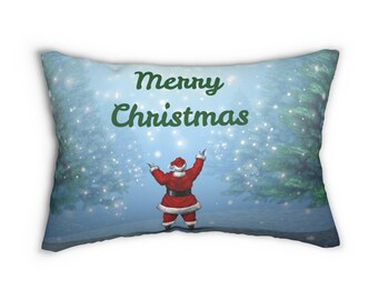 Puede incluir: Cojín rectangular navideño con una escena invernal. Papá Noel, con un traje rojo, está en el centro con los brazos levantados. Las palabras "Merry Christmas" están en verde sobre Papá Noel. El fondo es un bosque nevado con pinos.