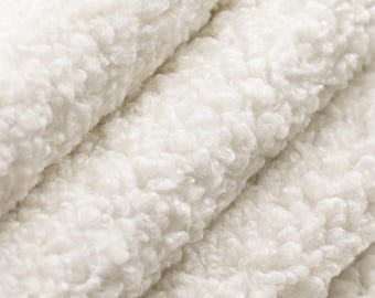 May include: Close-up of a folded, off-white, plush fabric. The material has a thick, textured surface with a soft, fluffy appearance. The folds create shadows and depth, highlighting the fabric's cozy texture. Ideal for blankets, throws, or apparel.