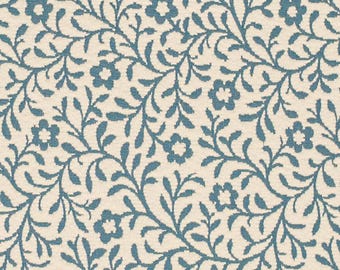 May include: A close-up of a cream-colored fabric with a repeating pattern of blue floral vines and flowers. The design is detailed and intricate, creating a textured appearance. The overall aesthetic is reminiscent of a classic, vintage style.