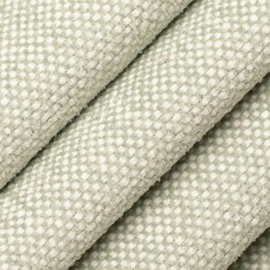 May include: Close-up of a textured fabric in a light green color with a pattern of small white dots. The fabric is folded, revealing its thickness and soft texture. Ideal for upholstery or textile projects.