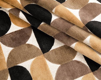 May include: Close-up of a folded fabric with a repeating geometric pattern. The design features semi-circles in black, brown, and tan against a white background. The fabric has a textured appearance, suggesting a woven material.