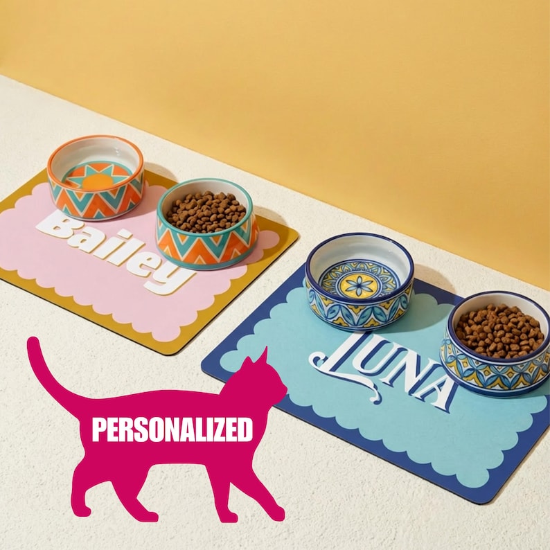 Personalizable pet placemat featuring a custom name design in retro script, shown with cat food and water bowls on top. This personalized pet feeding mat is perfect for cats and dogs, helping protect floors while adding stylish pet decor to kitchens, laundry rooms, or feeding stations.