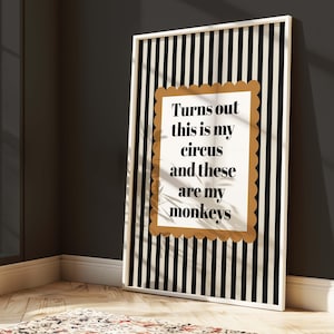 May include: A framed art print with a white border features a black and white striped background. The print has a gold scalloped border around the text: "Turns out this is my circus and these are my monkeys."