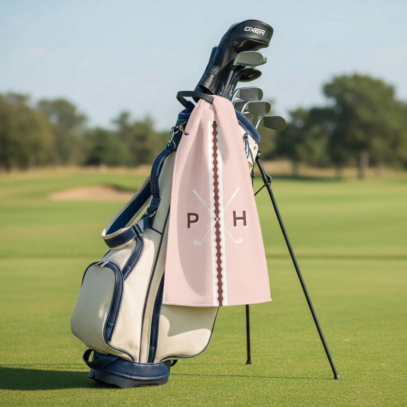 Personalizable golf towel featuring custom initials with crossed golf clubs design, displayed on a golf cart at the course. This personalized golf towel makes a thoughtful gift for golfers, golf dads, groomsmen, and tournament players, combining classic style with functional golf accessories.