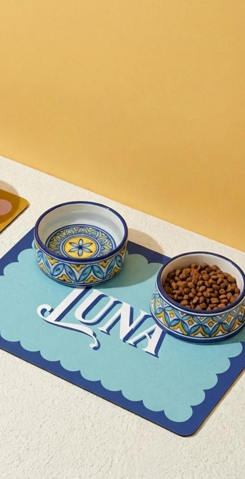 Custom pet bowl mat featuring a personalized name design, ideal for cats and dogs. This waterproof pet placemat keeps feeding areas clean while adding aesthetic pet decor to your home. A must-have personalized pet accessory for modern pet parents and a great gift idea for cat lovers and dog owners.