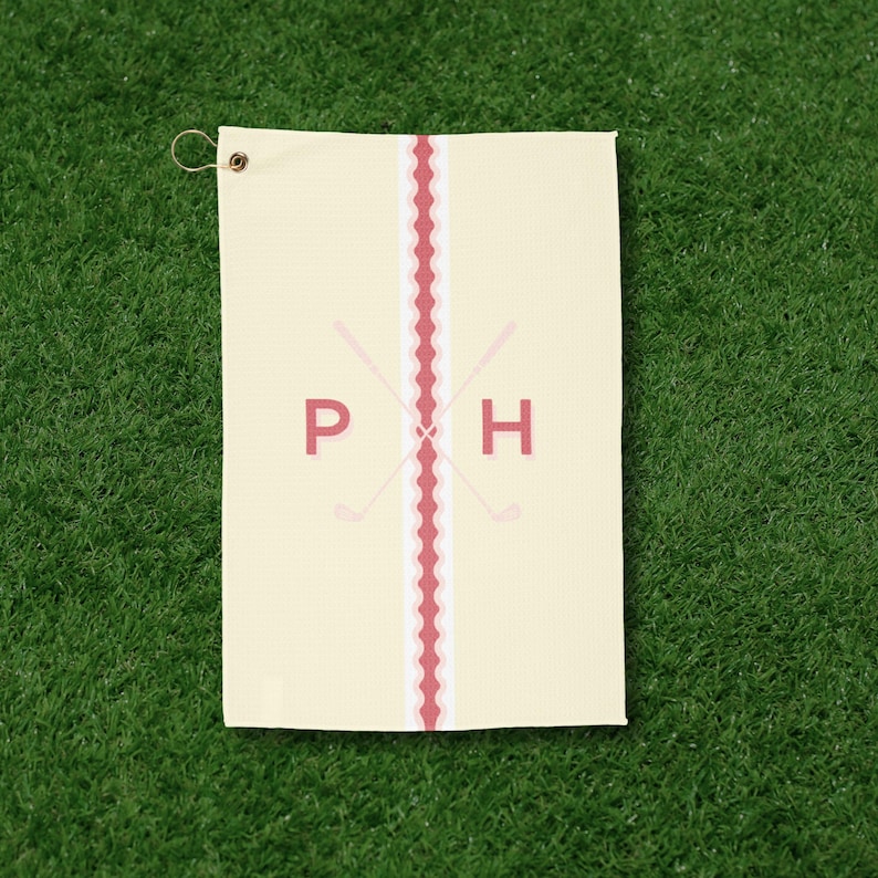 Personalized golf towel with custom monogram lettering and minimalist golf club design, shown at a golf course. This embroidered-style golf cart towel is ideal for golf tournaments, bachelor parties, Father’s Day gifts, and stylish golf accessories.
